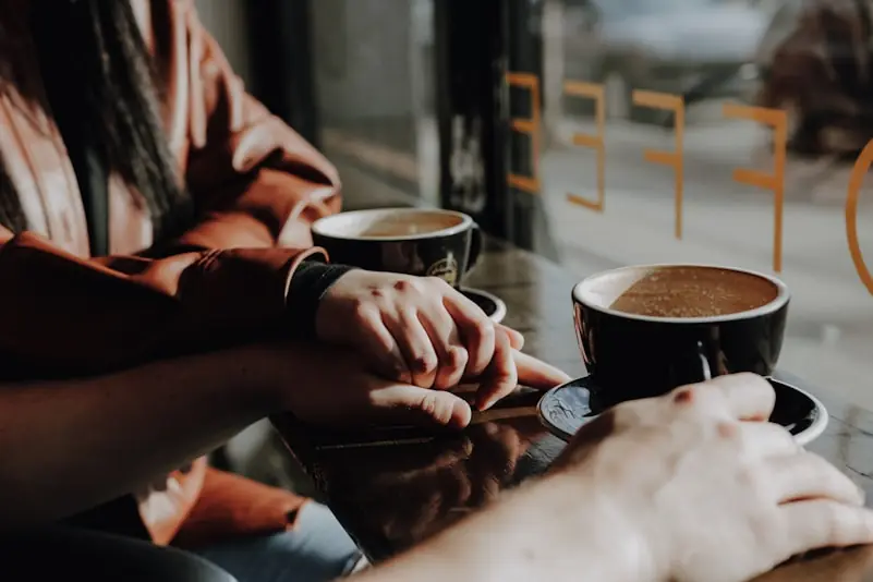 People holding hands while drinking coffee at a cafe
